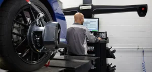 n a bustling garage, a man focuses on fixing a car, highlighting the craftsmanship at Lexology Auto Shop