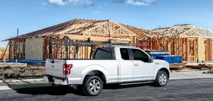 A white truck with a roof rack parked in front of a construction zone, showcasing the Rack-it Storage Rack. Photography by Dogs of Design